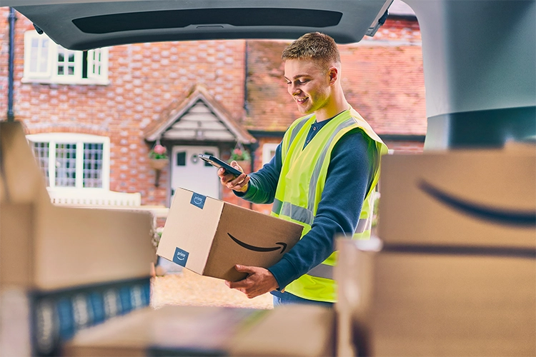 Man in yellow vest scanning a pacakge in front of a brick house